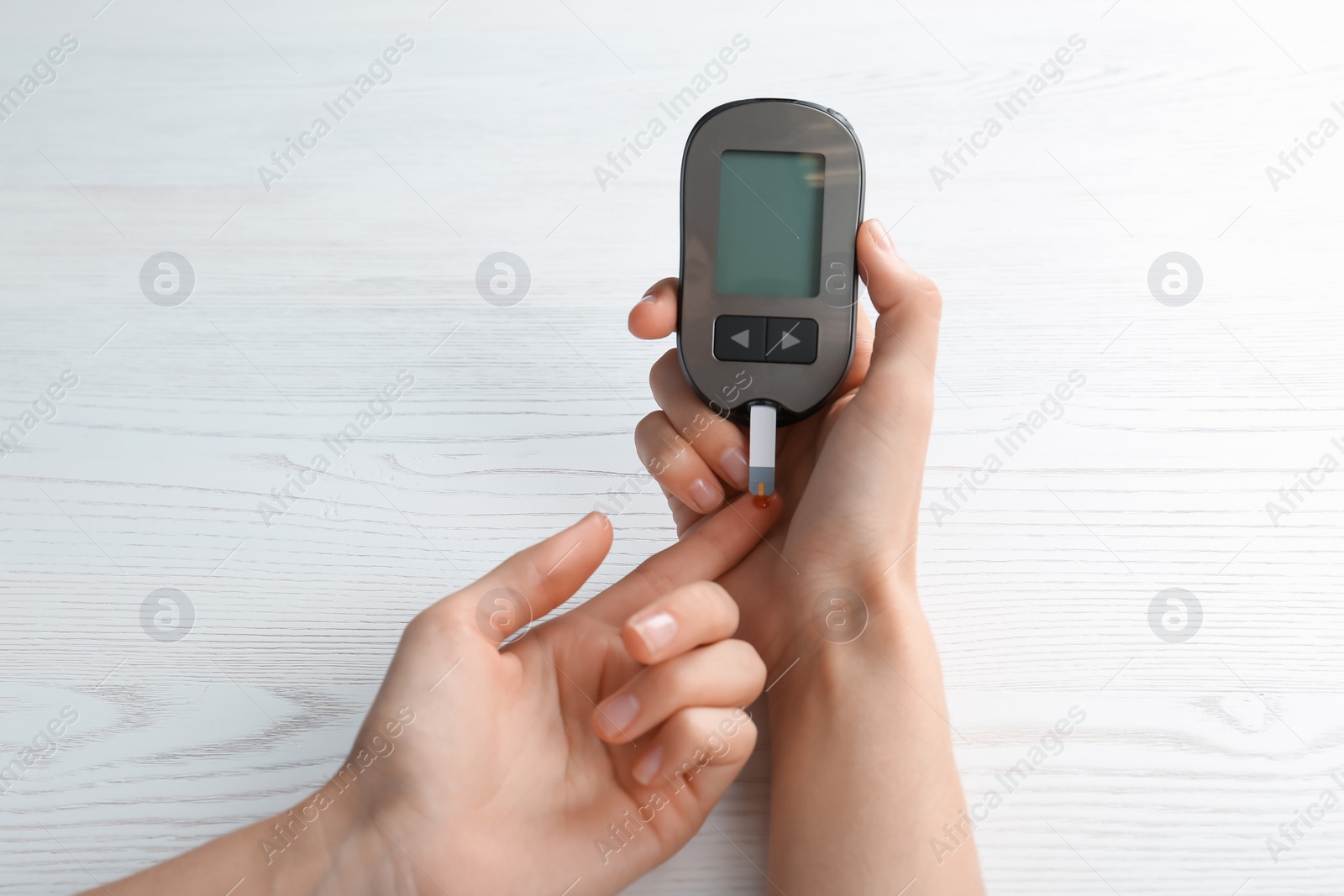 Photo of Woman checking blood sugar level with glucometer at table. Diabetes test