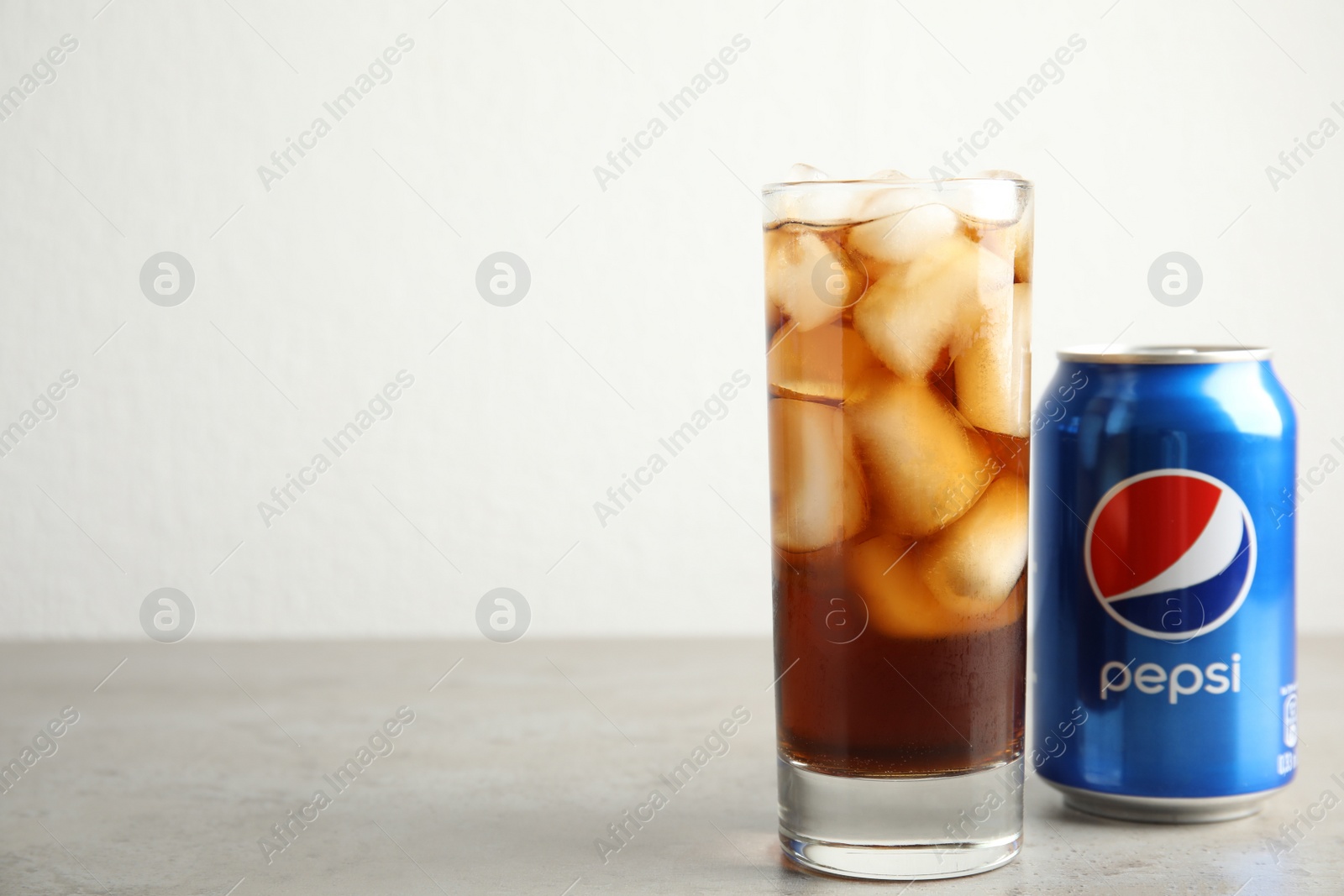 Photo of MYKOLAIV, UKRAINE - FEBRUARY 10, 2021: Glass and can of Pepsi on grey table. Space for text