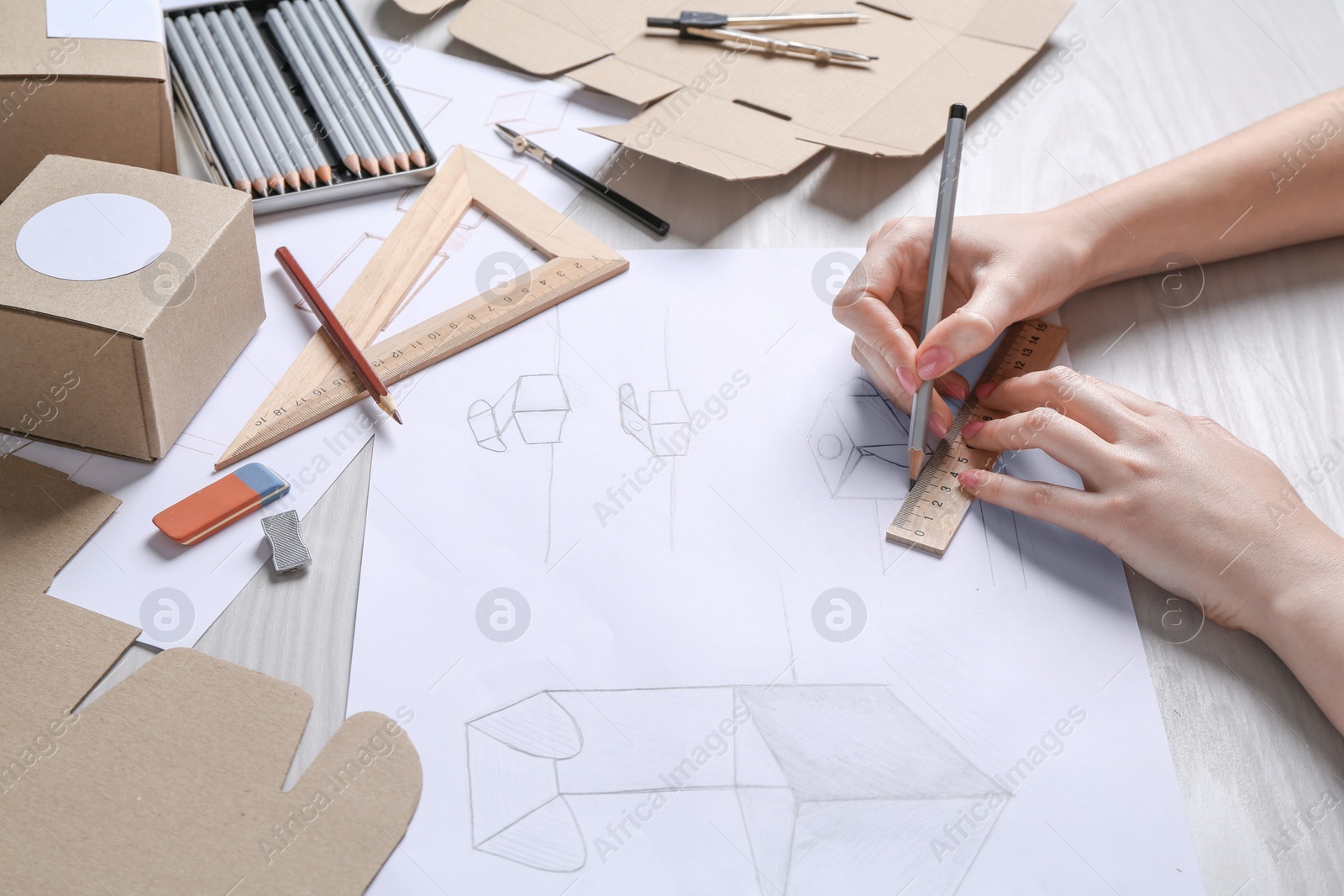 Photo of Woman creating packaging design at light wooden table, closeup