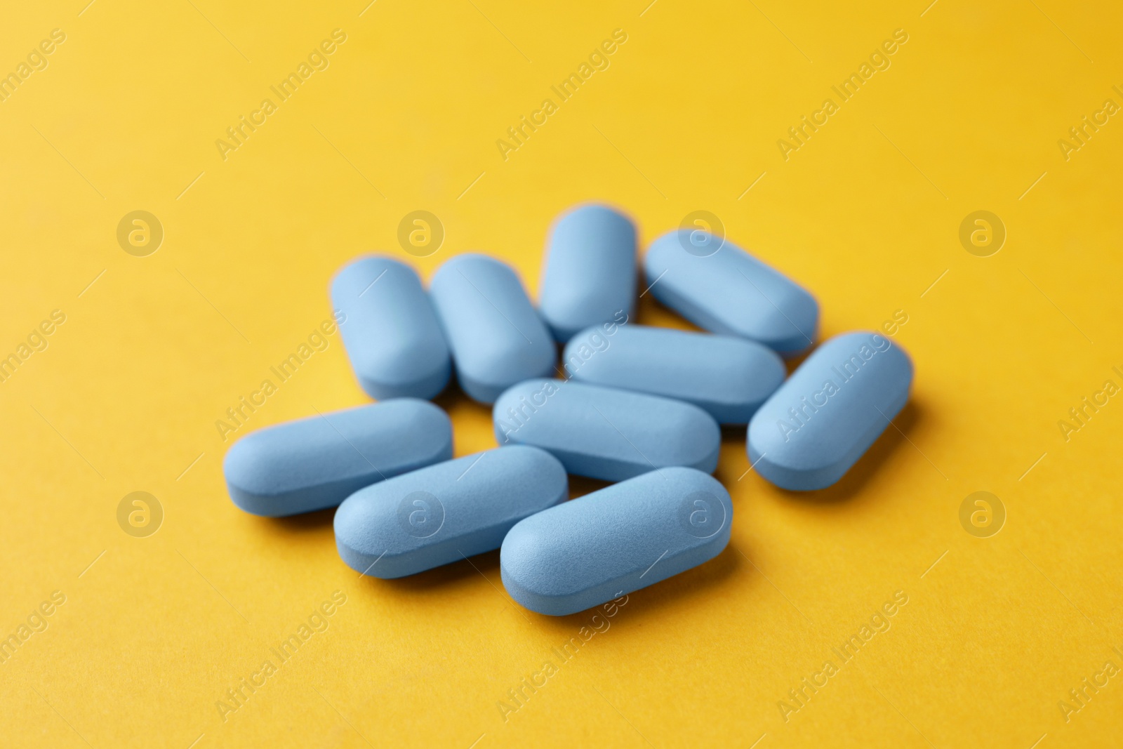 Photo of Many pills on orange background. Potency problem