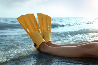 Woman in flippers near sea on beach, closeup
