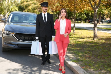 Photo of Handsome driver with shopping bags and young businesswoman near car outdoors