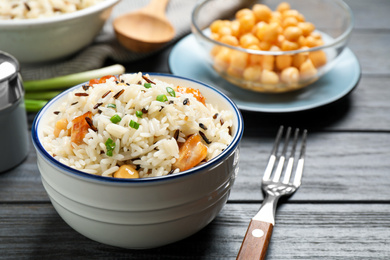 Photo of Delicious rice pilaf with chicken on black wooden table