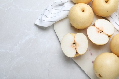 Photo of Cut and whole apple pears on light grey table, flat lay. Space for text