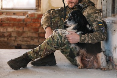 Photo of Ukrainian soldier sitting with stray dog in abandoned building, closeup