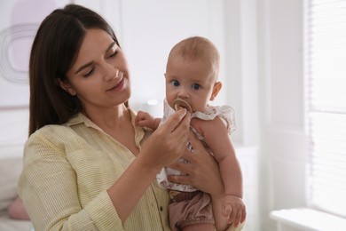 Happy mother giving pacifier to her cute little baby at home