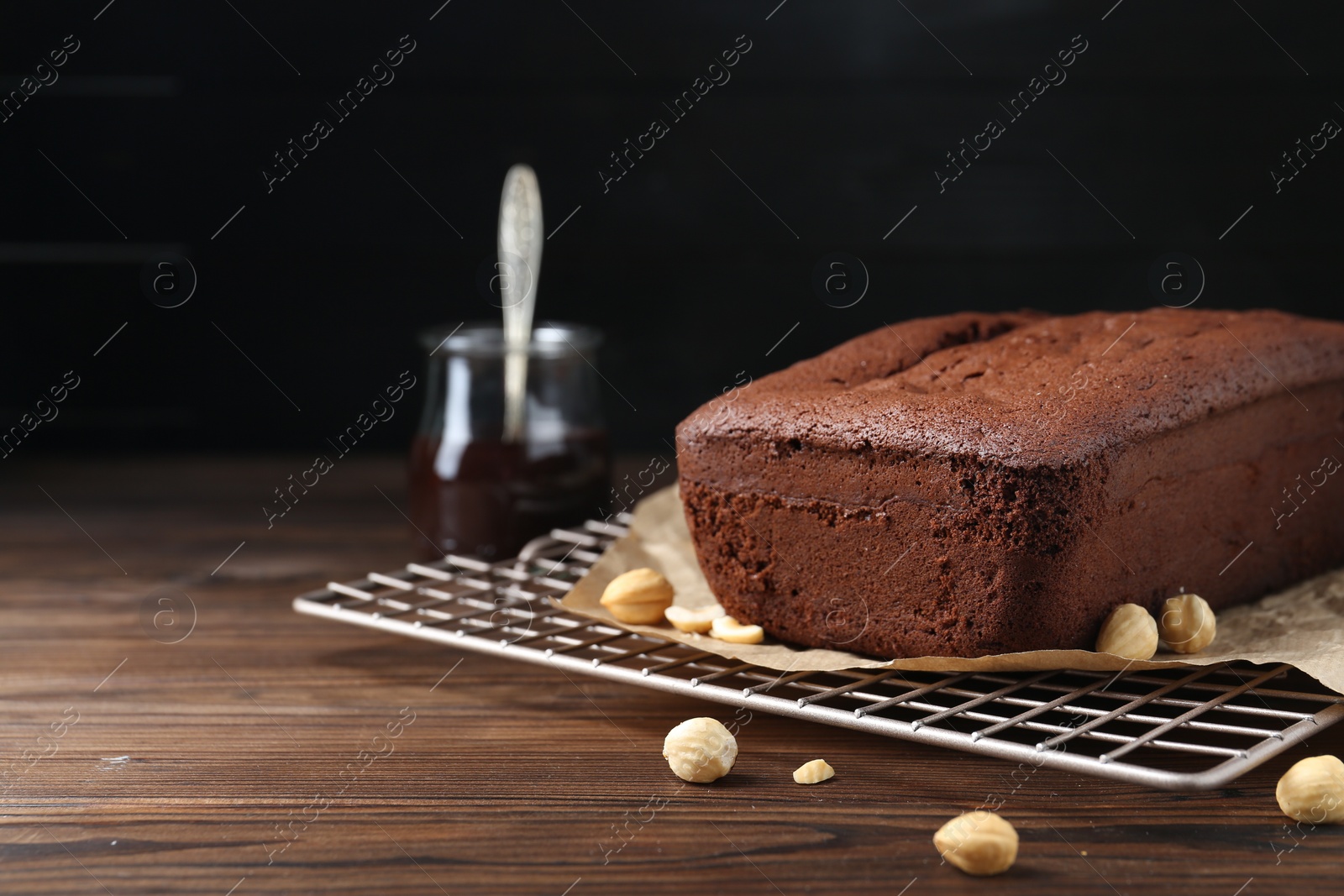 Photo of Delicious chocolate sponge cake and nuts on wooden table. Space for text