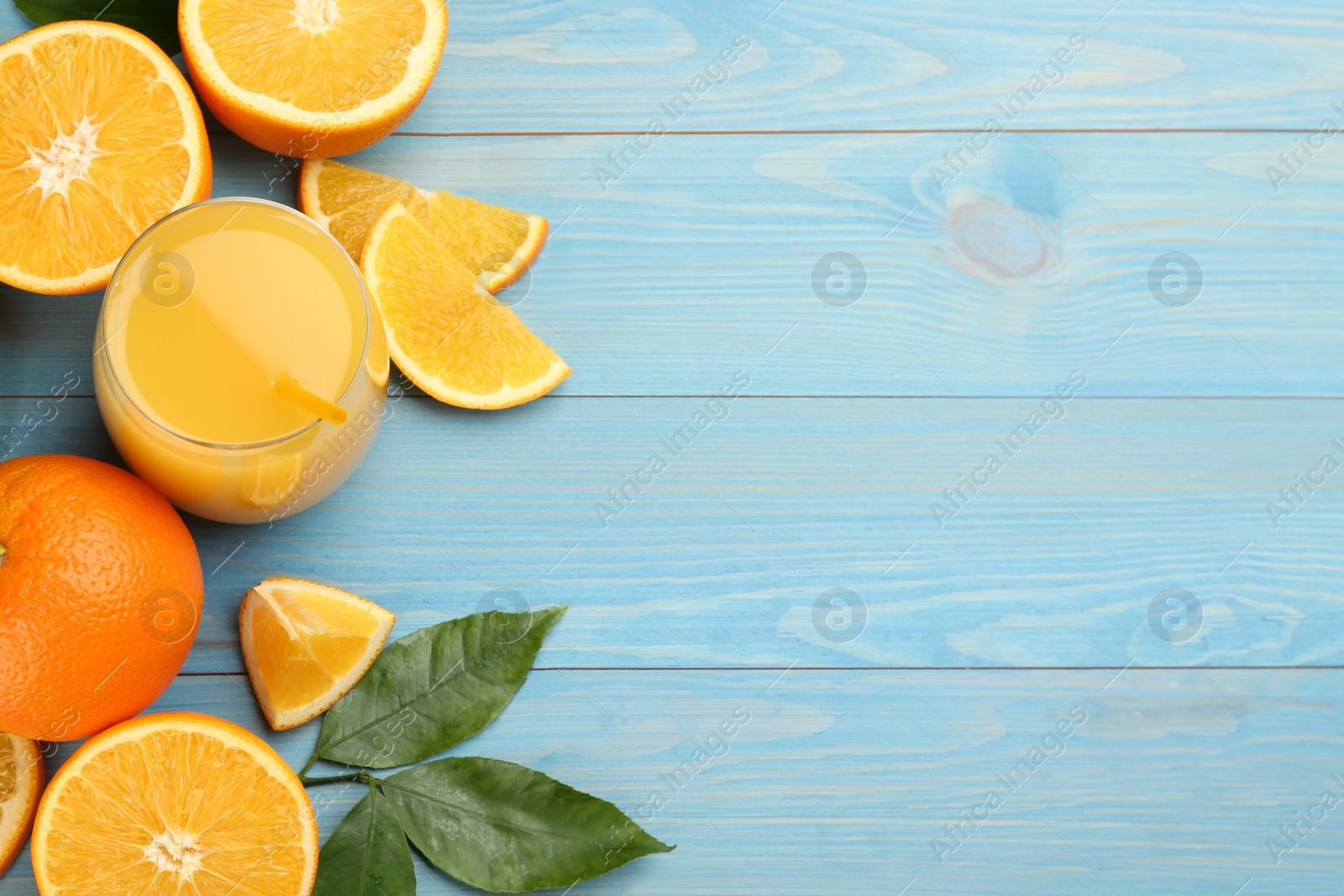 Photo of Delicious orange juice and fresh fruits on light blue wooden table, flat lay. Space for text