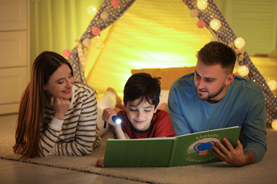 Photo of Family with flashlight reading book at home