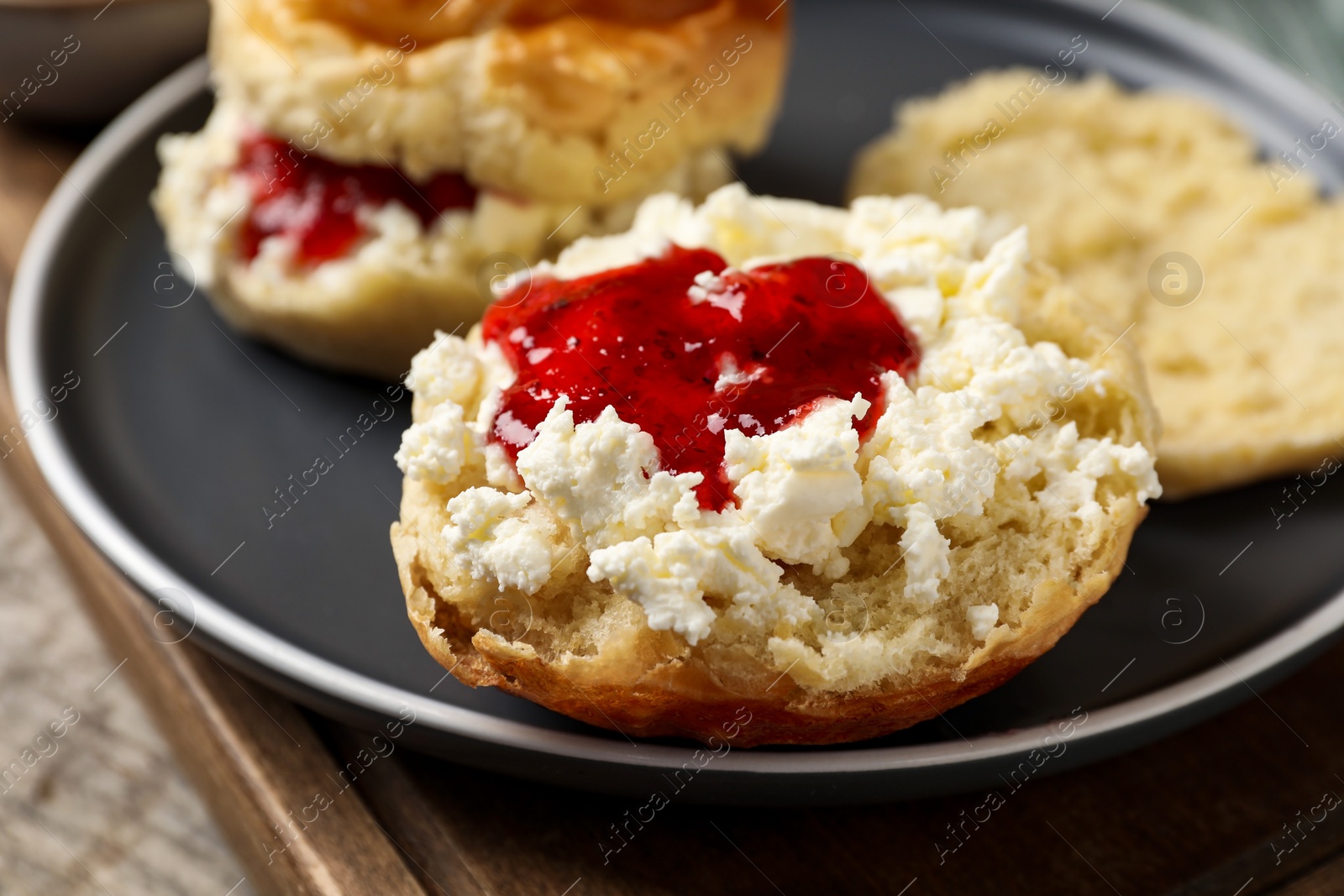 Photo of Freshly baked soda water scones with cranberry jam and butter on wooden table, closeup