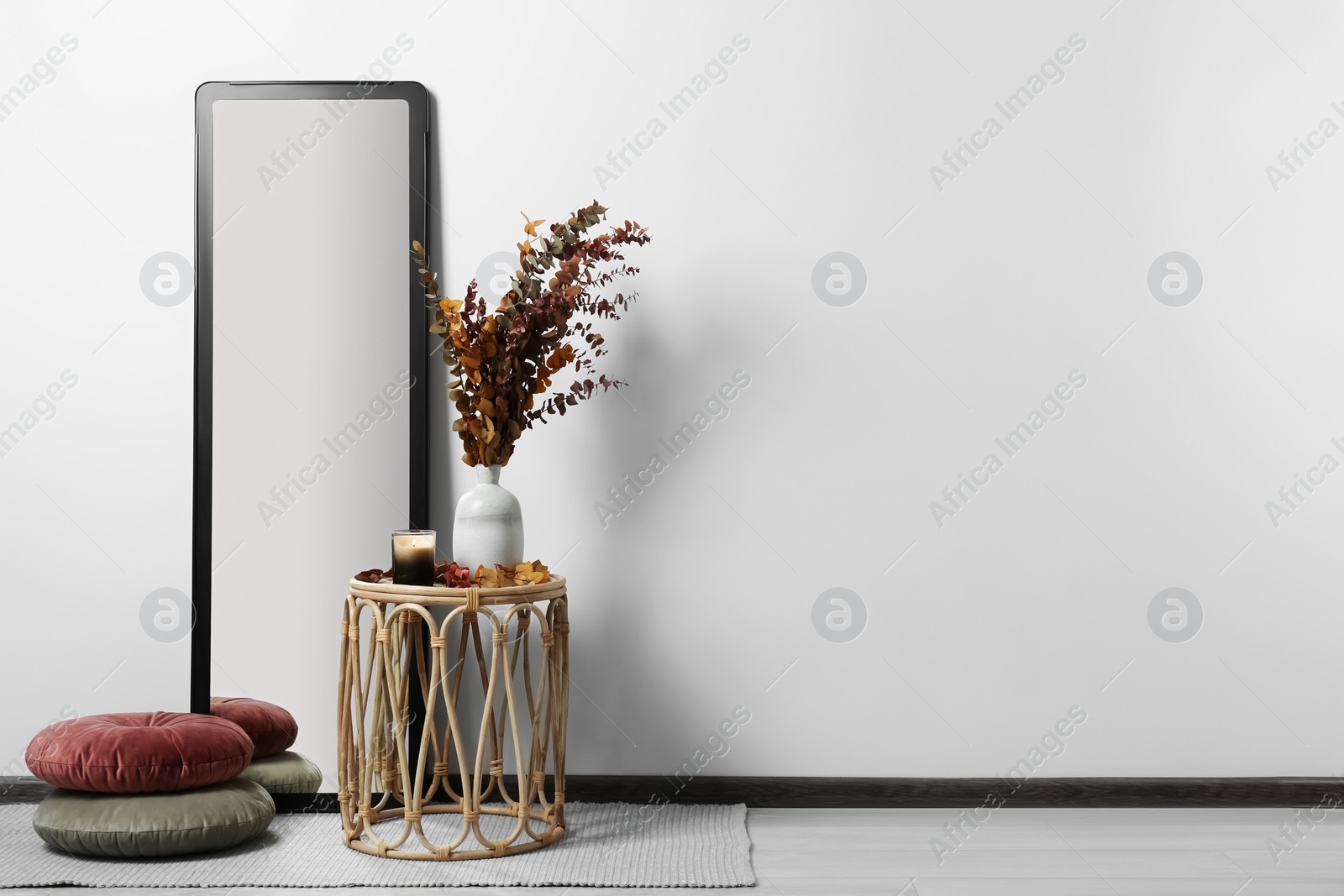 Photo of Table, mirror and pillows on floor near white wall, space for text