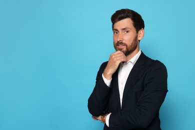 Portrait of handsome bearded man in suit on light blue background. Space for text