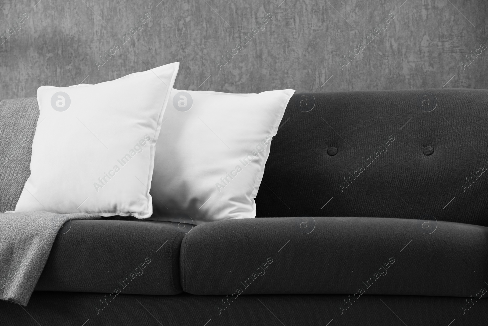 Photo of Soft white pillows and blanket on sofa indoors