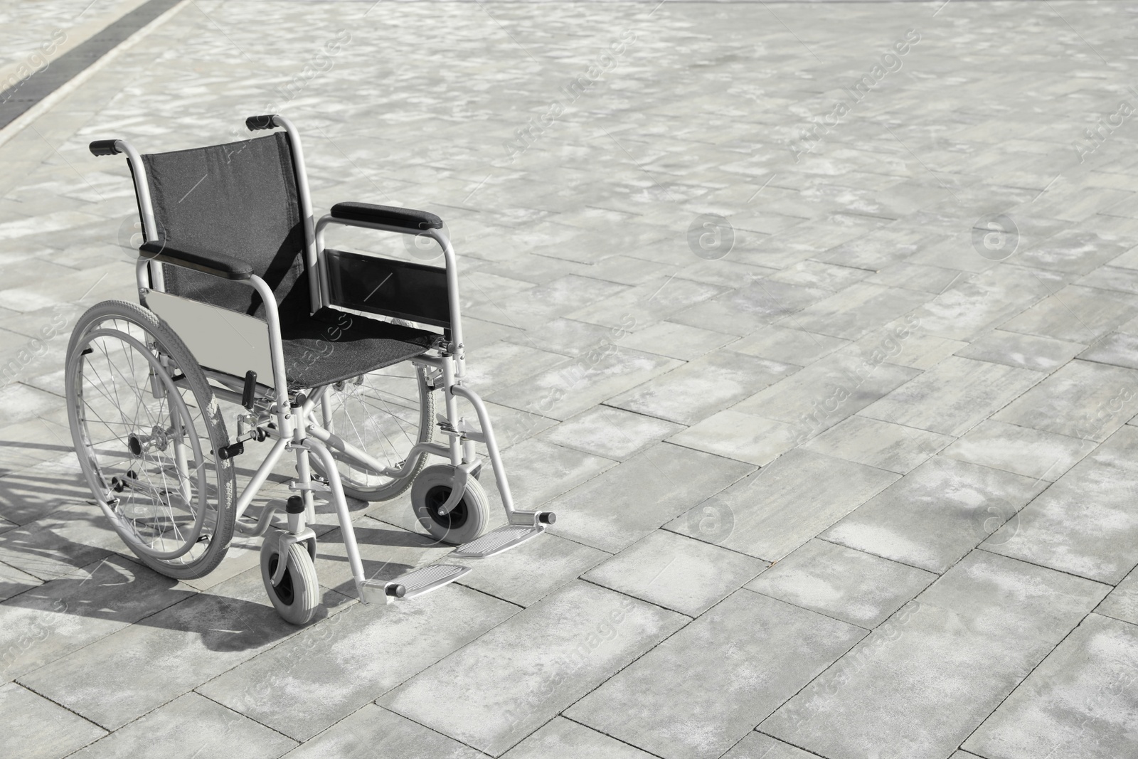 Photo of Empty wheelchair outdoors on sunny day. Space for text