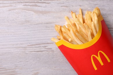 MYKOLAIV, UKRAINE - AUGUST 12, 2021: Big portion of McDonald's French fries on white wooden table, top view. Space for text