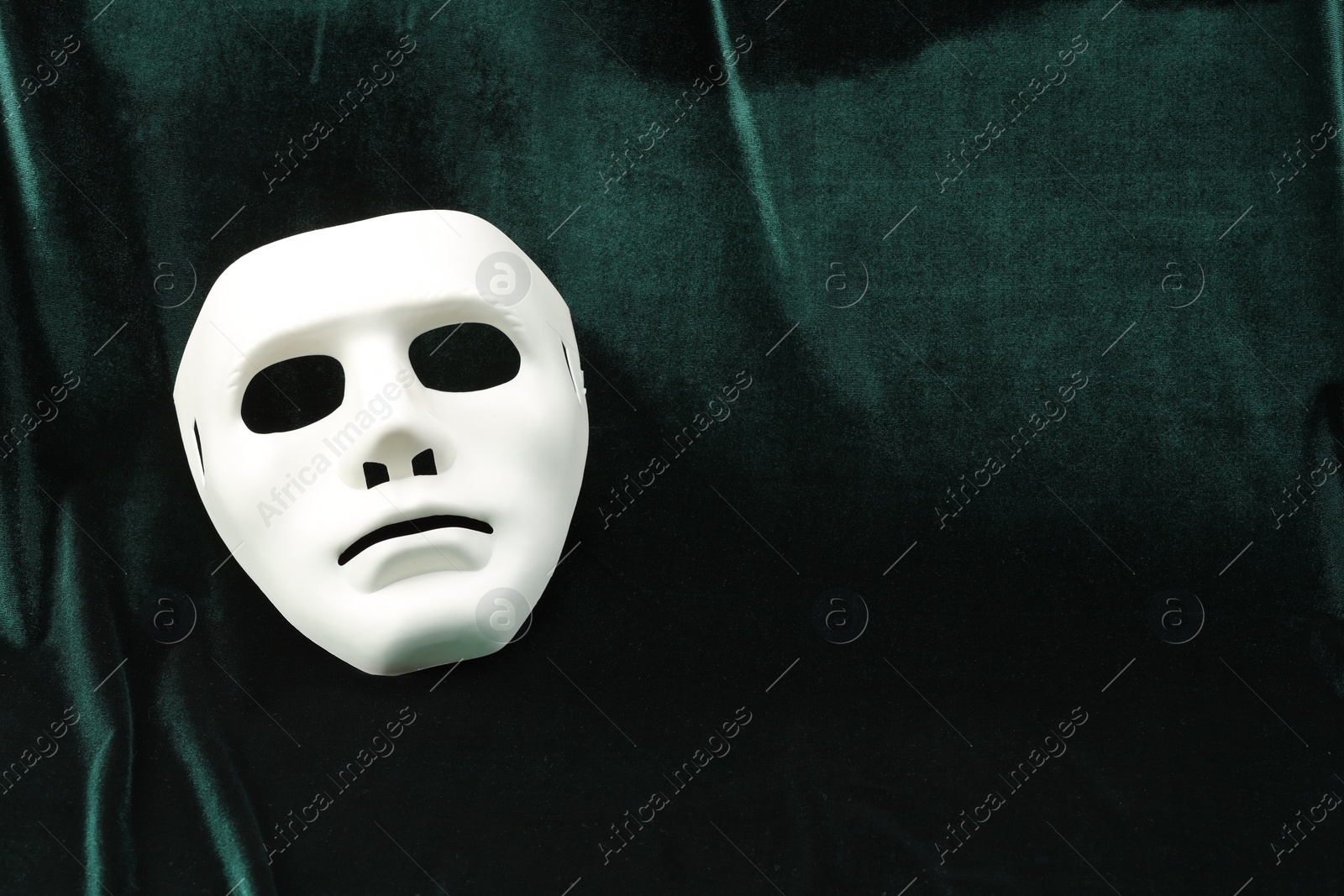Photo of Theater arts. White mask on green fabric, top view. Space for text