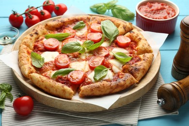 Photo of Delicious Margherita pizza and ingredients on light blue wooden table