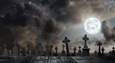 Image of Wooden surface and moonlit graveyard with old creepy headstones. Halloween banner design