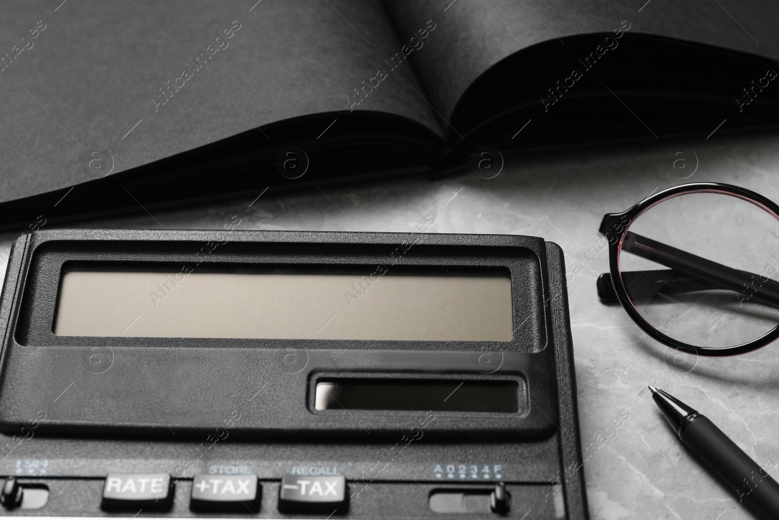 Photo of Calculator, glasses, pen and notebook on marble table, closeup. Tax accounting