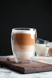 Photo of Glass with delicious caramel latte on table