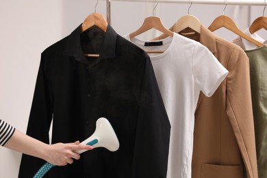 Woman steaming black shirt on white background, closeup