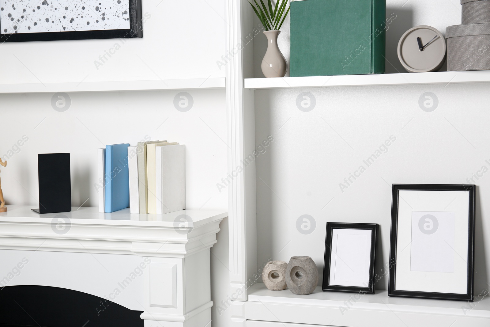 Photo of White shelves and fireplace with different decor indoors. Interior design