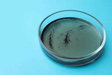 Photo of Petri dish with bacteria colony on light blue background