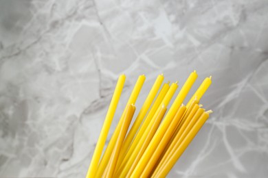 Photo of Many church candles on grey background, closeup. Space for text