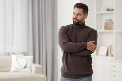 Photo of Handsome man in stylish sweater at home, space for text