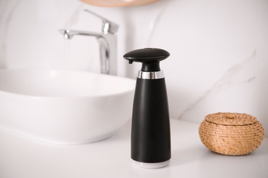 Photo of Modern automatic soap dispenser on countertop in bathroom