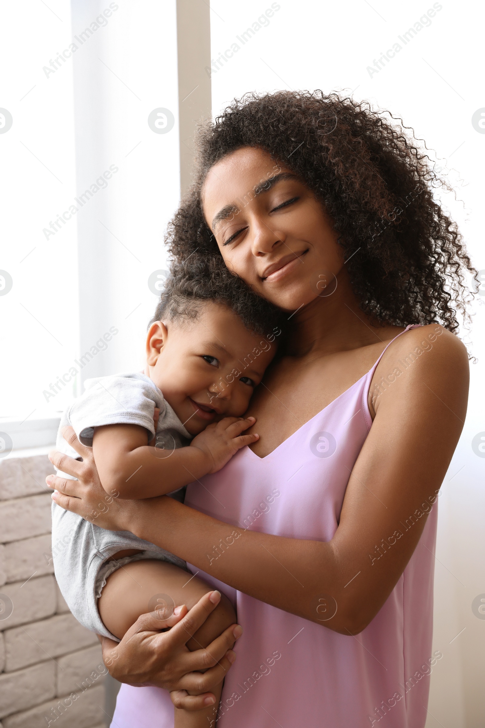 Photo of African-American woman with her baby at home. Happiness of motherhood