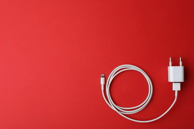 Photo of USB charger on red background, top view. Space for text
