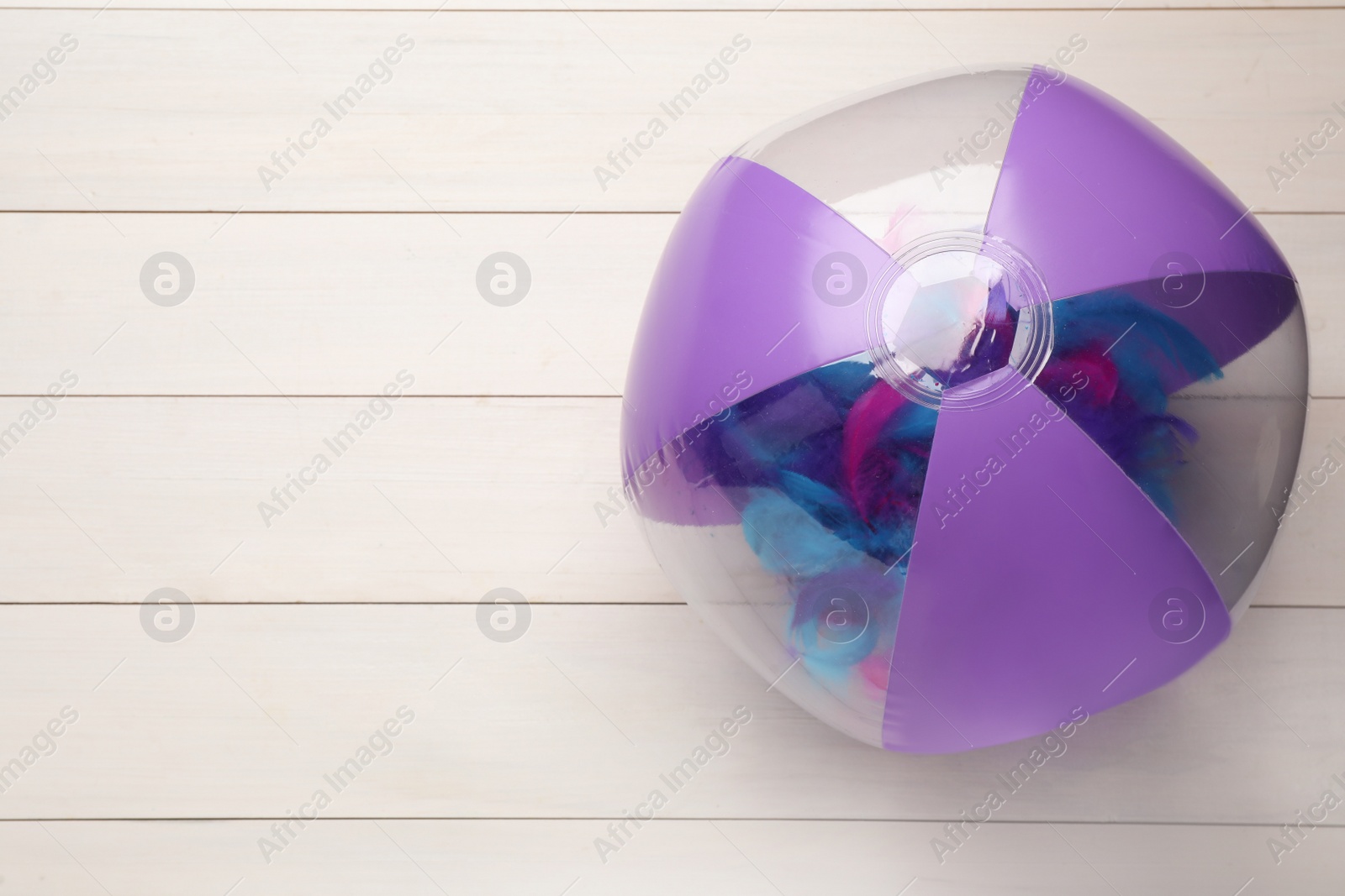 Photo of Bright beach ball on white wooden background, top view. Space for text
