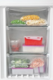 Different packed frozen products in refrigerator, closeup