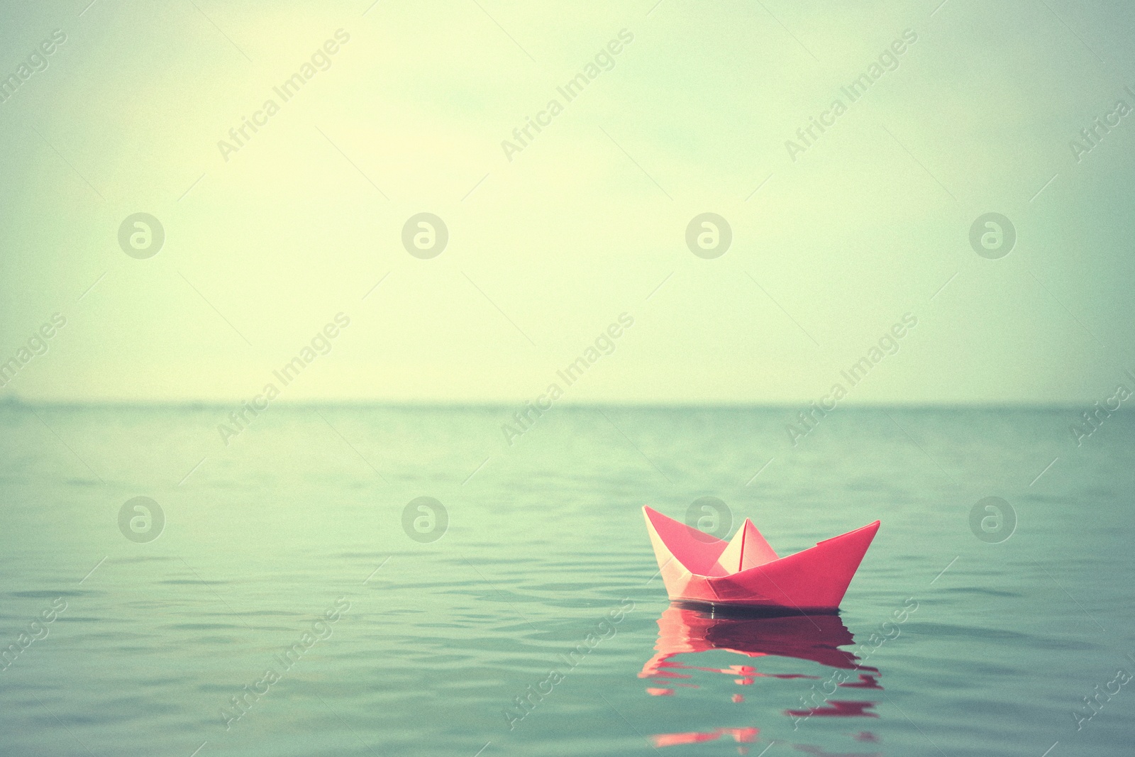 Image of Pink paper boat floating on river. Retro photo effect