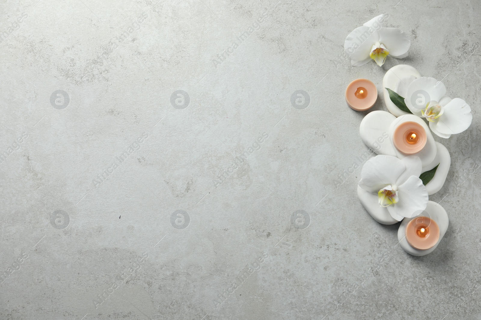 Photo of Flat lay composition with burning candles and spa stones on light grey table. Space for text