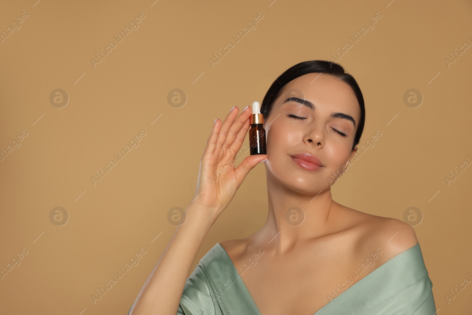 Photo of Young woman with bottle of essential oil on beige background. Space for text