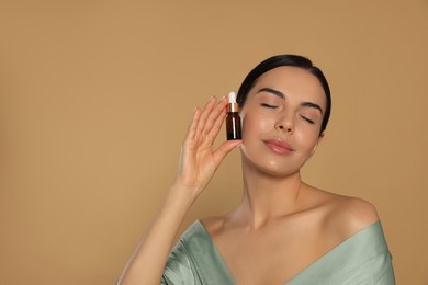 Young woman with bottle of essential oil on beige background. Space for text