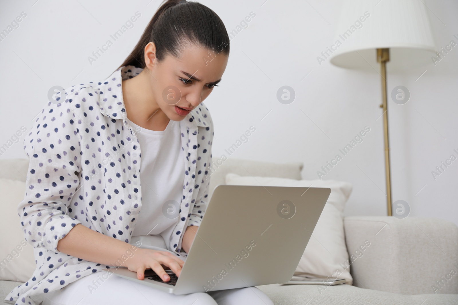 Photo of Emotional young woman with laptop at home. Online hate concept