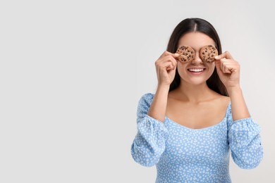 Photo of Young woman with chocolate chip cookies on white background, space for text