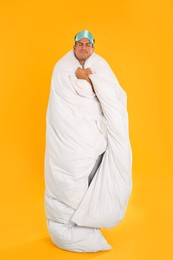 Photo of Man wrapped with blanket in sleeping mask on yellow background