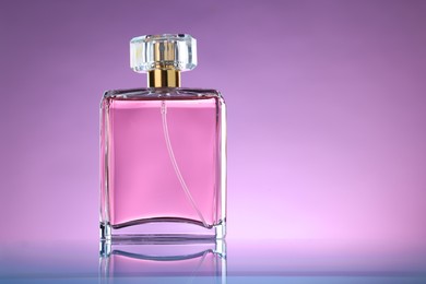 Luxury women's perfume in bottle on violet background. Space for text