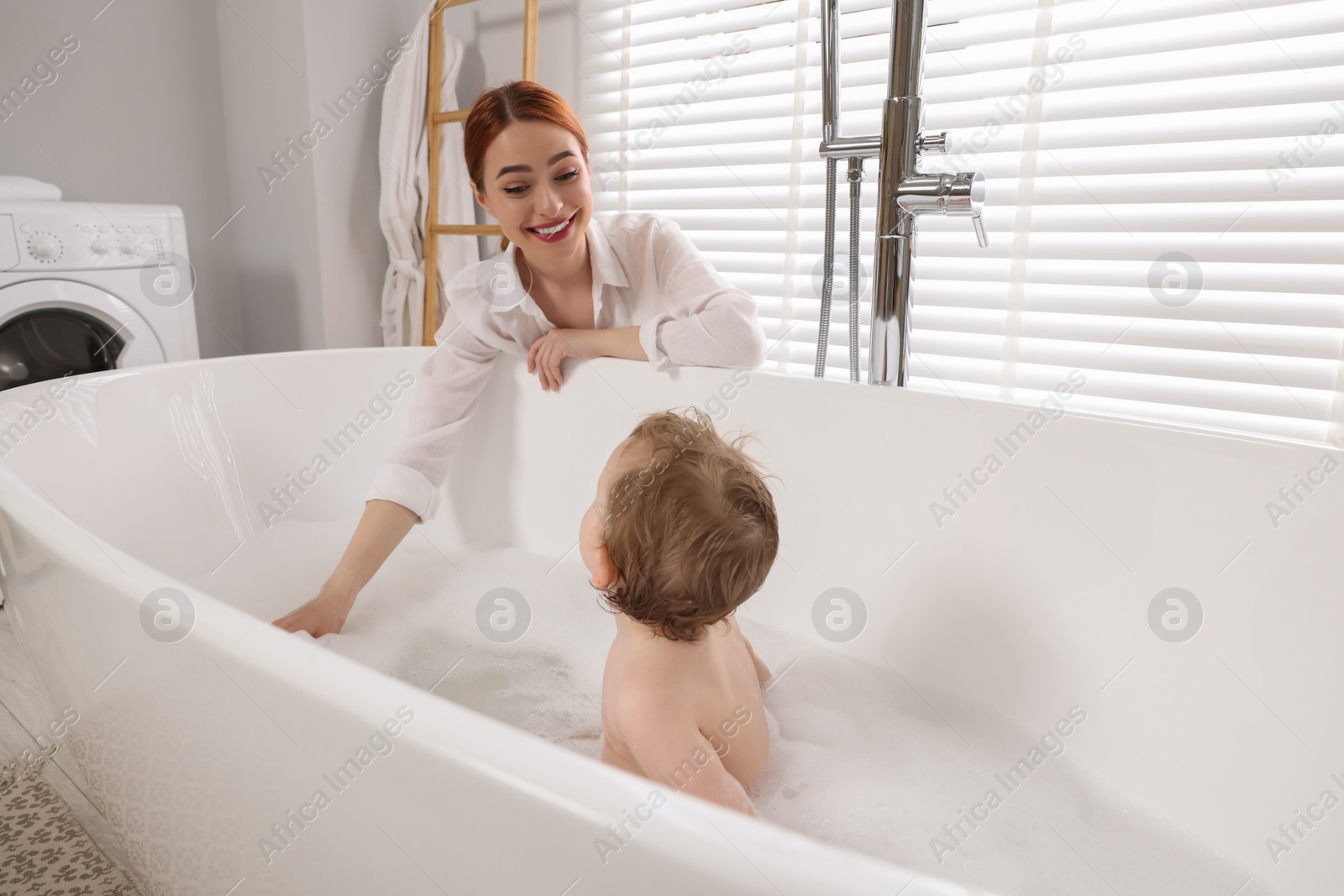 Photo of Mother washing her little baby in tub at home