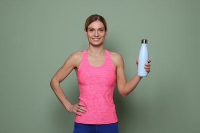 Photo of Sportswoman with thermo bottle on green background