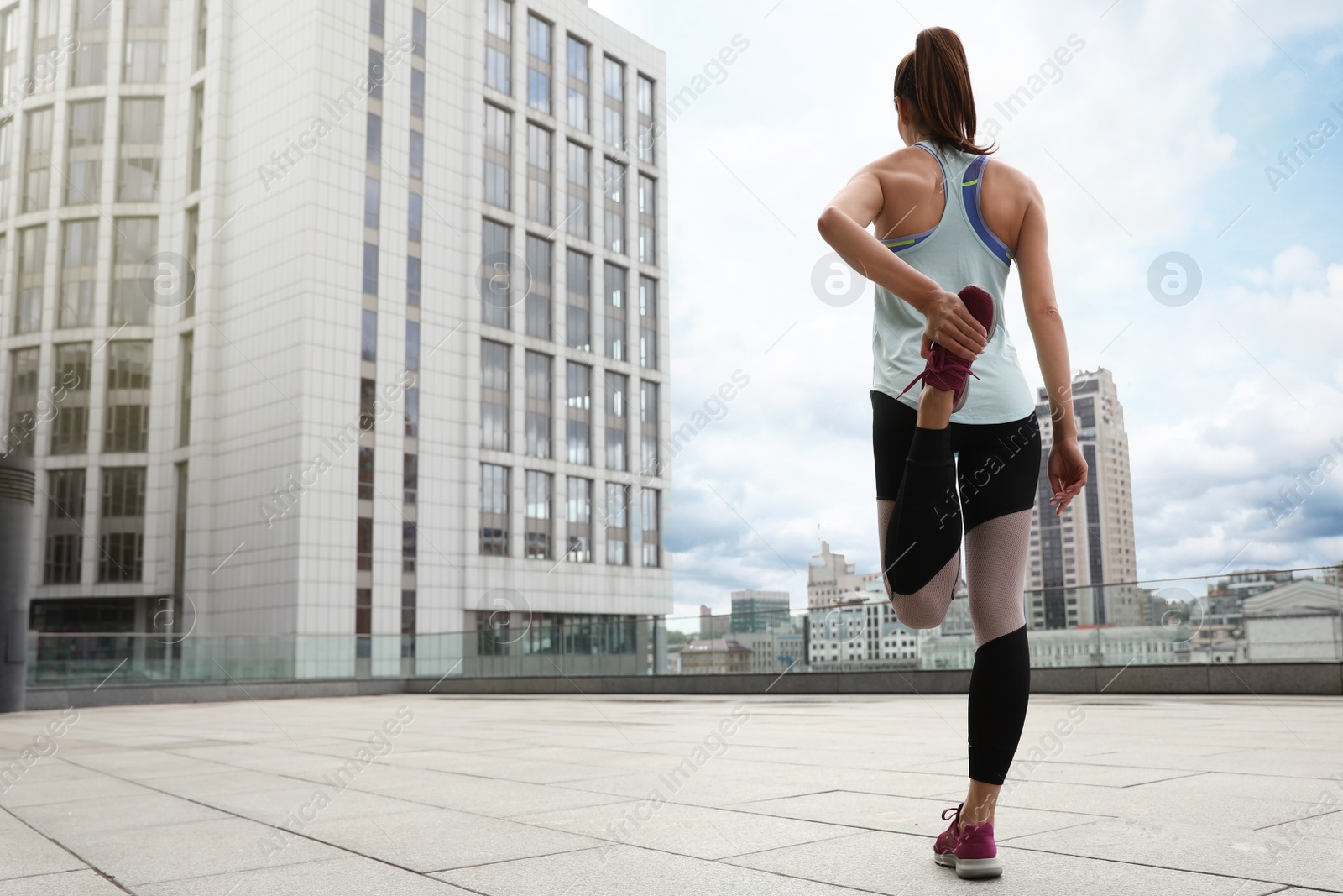 Photo of Woman stretching before morning fitness outdoors, back view
