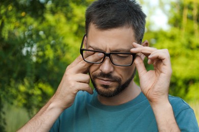 Man suffering from eyestrain outdoors on sunny day