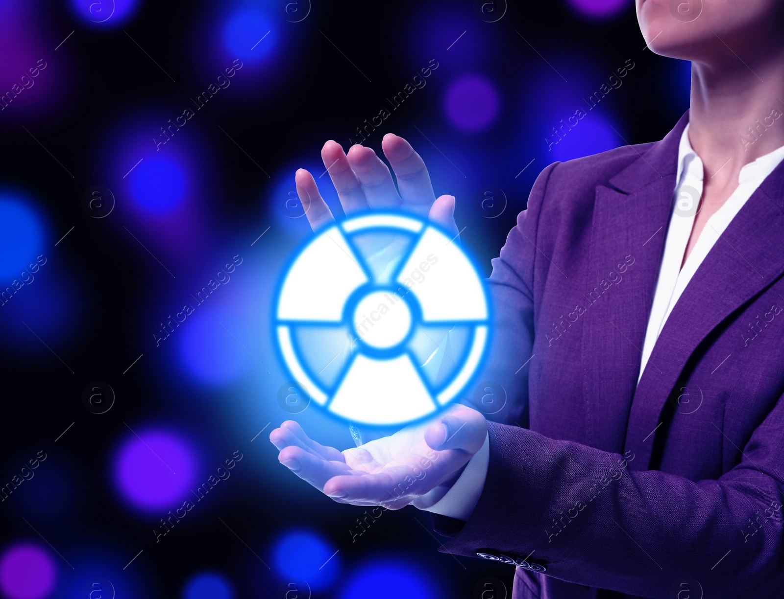 Image of Woman holding glowing radiation warning symbol on dark background with blue and purple blurred lights, closeup