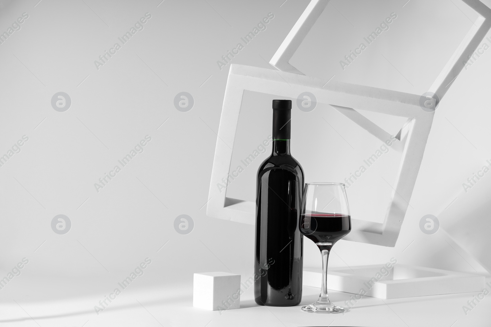 Photo of Stylish presentation of delicious red wine in bottle and glass on white background. Space for text