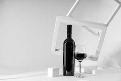 Photo of Stylish presentation of delicious red wine in bottle and glass on white background. Space for text