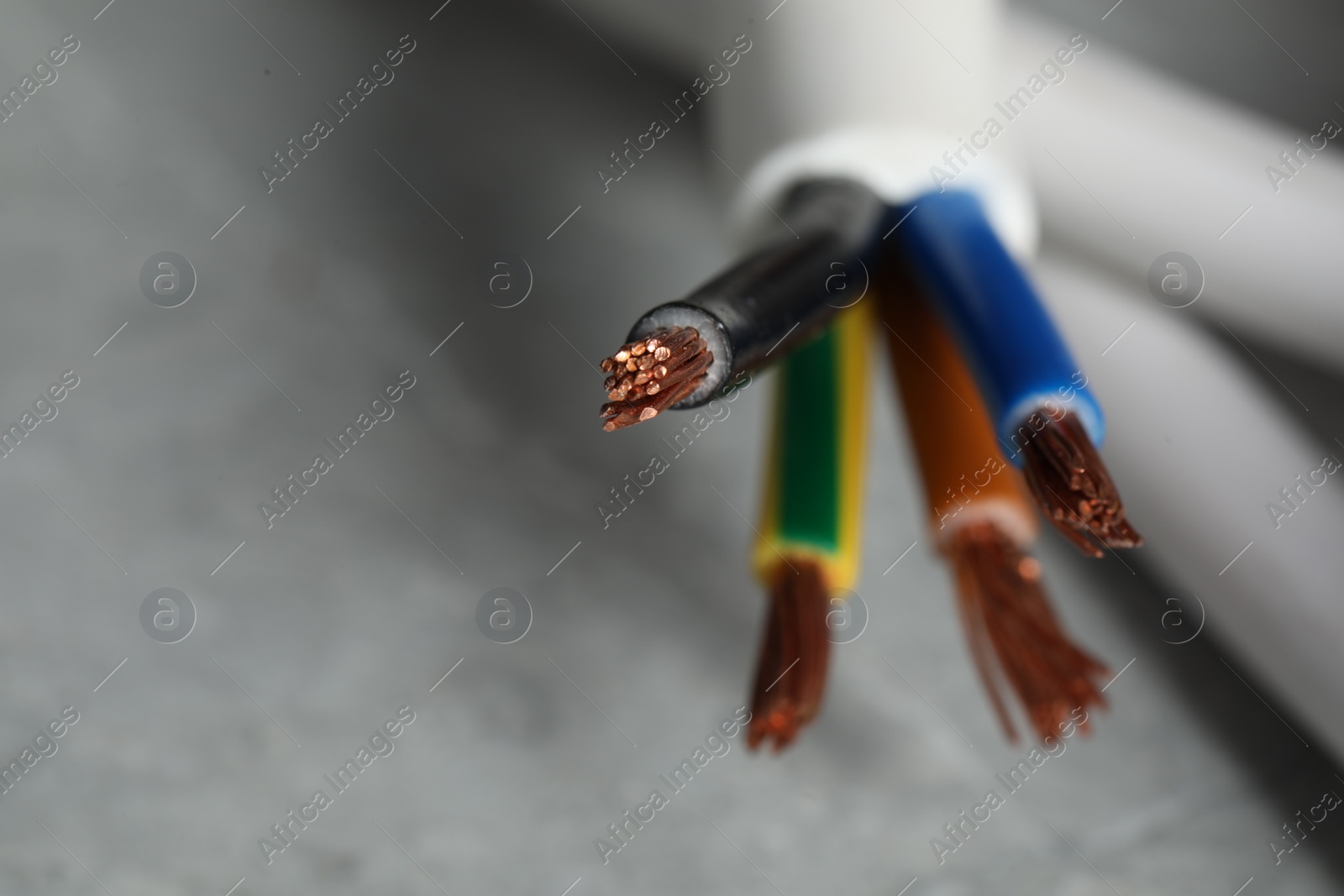 Photo of Colorful electrical wire on blurred background, closeup. Space for text